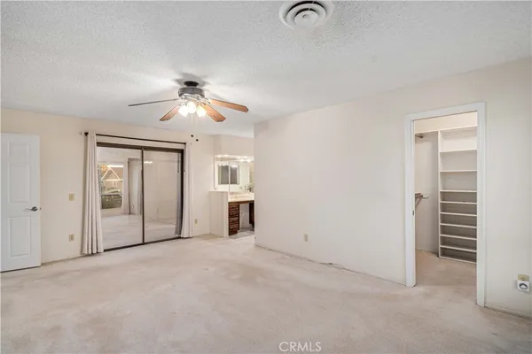 an empty room with closet and a ceiling fan