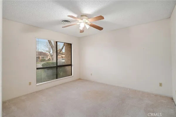 an empty room with windows and fan