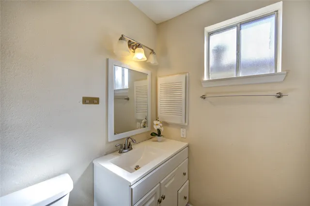 a bathroom with a sink mirror vanity and toilet