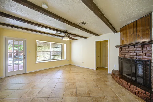 a view of an empty room with a fireplace and a window