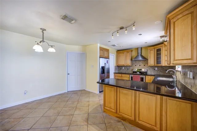 a kitchen with stainless steel appliances granite countertop a sink counter space cabinets and a chandelier