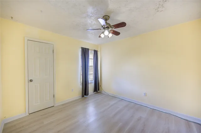 a view of a room with wooden floor and a ceiling fan