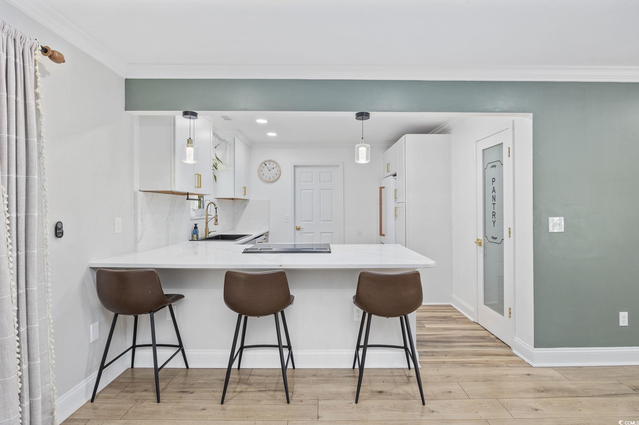 118 Sly Fox Trail Myrtle Beach, SC 29588 - Photo 14 of 40 Kitchen featuring a peninsula, a breakfast bar, white cabinets, light wood-style floors, and light stone countertops