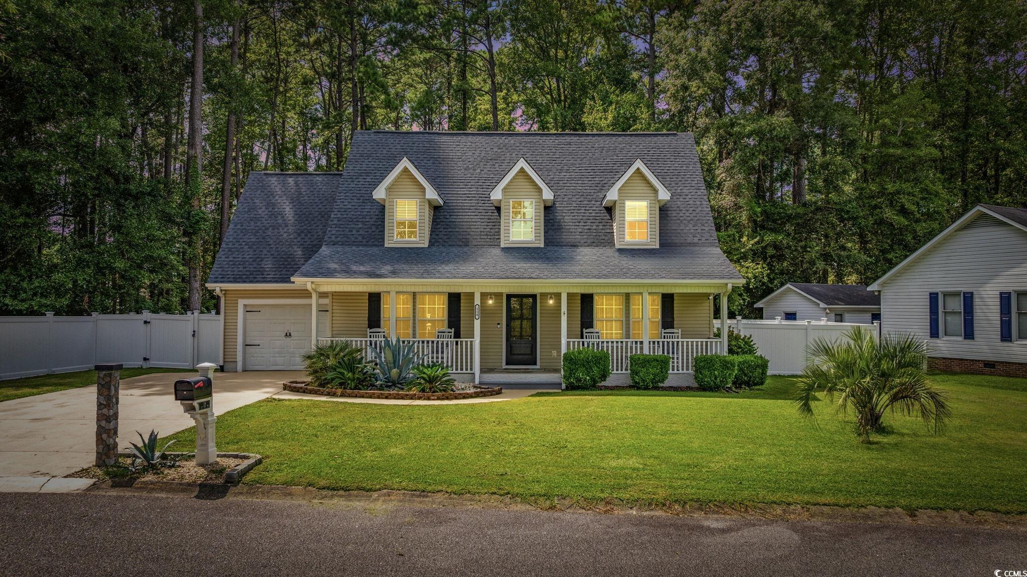 118 Sly Fox Trail Myrtle Beach, SC 29588 - Photo 2 of 40 Cape cod-style house featuring roof with shingles, covered porch, concrete driveway, an attached garage, and view of scattered trees