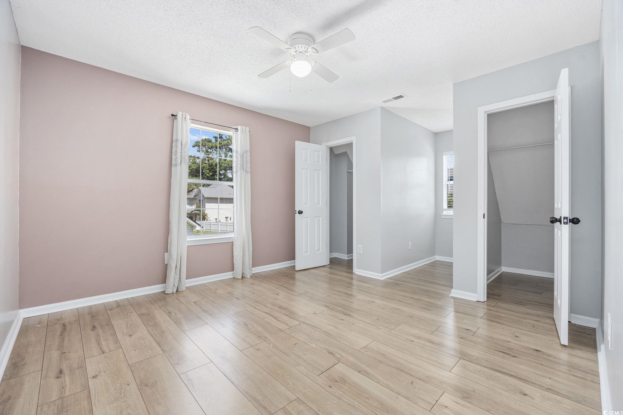 118 Sly Fox Trail Myrtle Beach, SC 29588 - Photo 22 of 40 Unfurnished bedroom featuring light wood finished floors, ceiling fan, a textured ceiling, and a walk in closet