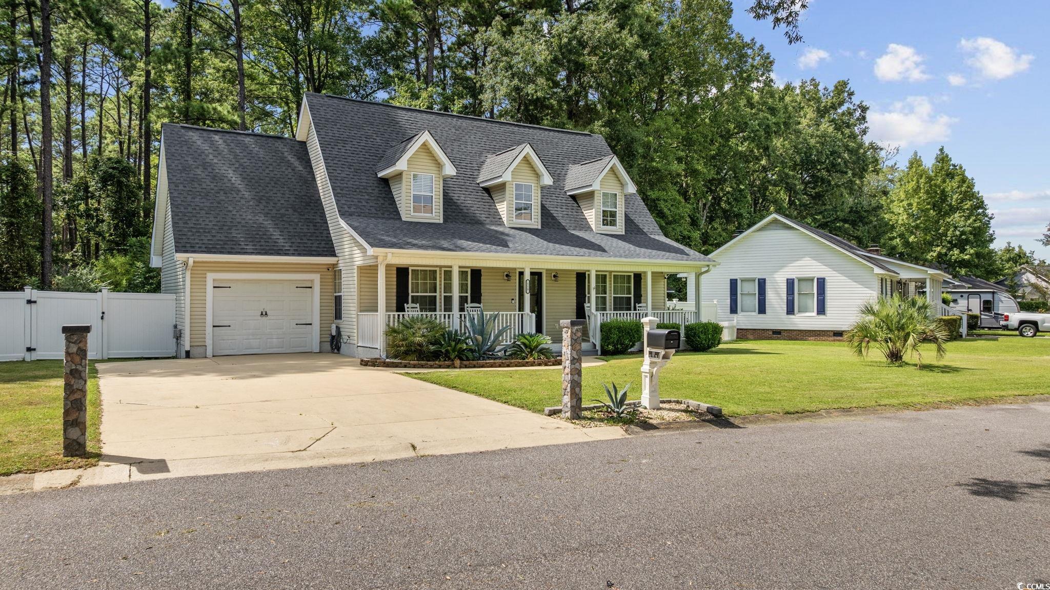 118 Sly Fox Trail Myrtle Beach, SC 29588 - Photo 3 of 40 New england style home featuring a porch, a shingled roof, concrete driveway, a garage, and a gate