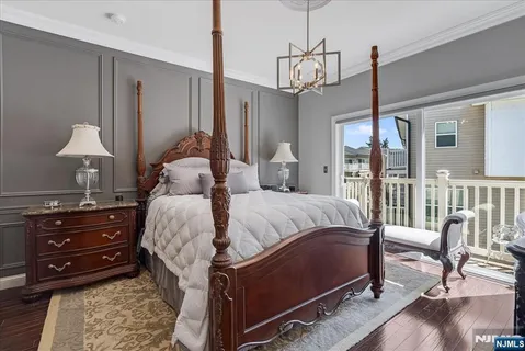 a bedroom with a bed a chandelier and flat screen tv