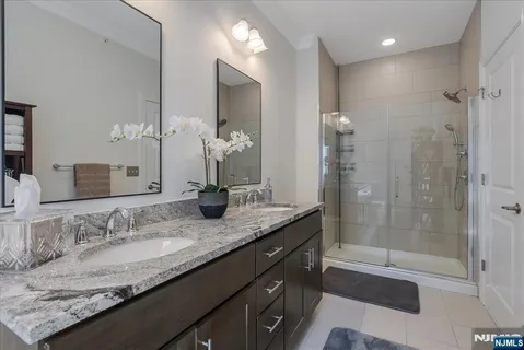 a bathroom with a granite countertop sink a mirror and a shower