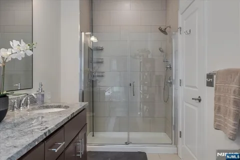 a bathroom with a granite countertop sink a mirror and shower