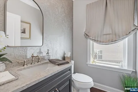 a bathroom with a granite countertop sink a toilet and a mirror