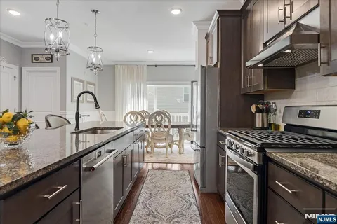 a kitchen with granite countertop a stove a sink and a refrigerator