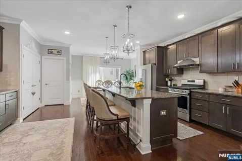 a kitchen with kitchen island granite countertop a sink cabinets and stainless steel appliances