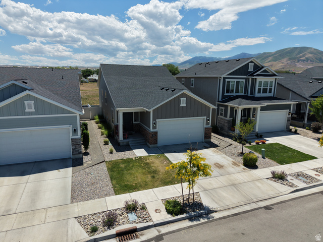 7687 West Mount Elinor Road Magna, UT 84044 - Photo 42 of 43 Modern residential exterior featuring a two-car garage, stone accents, and a covered entryway