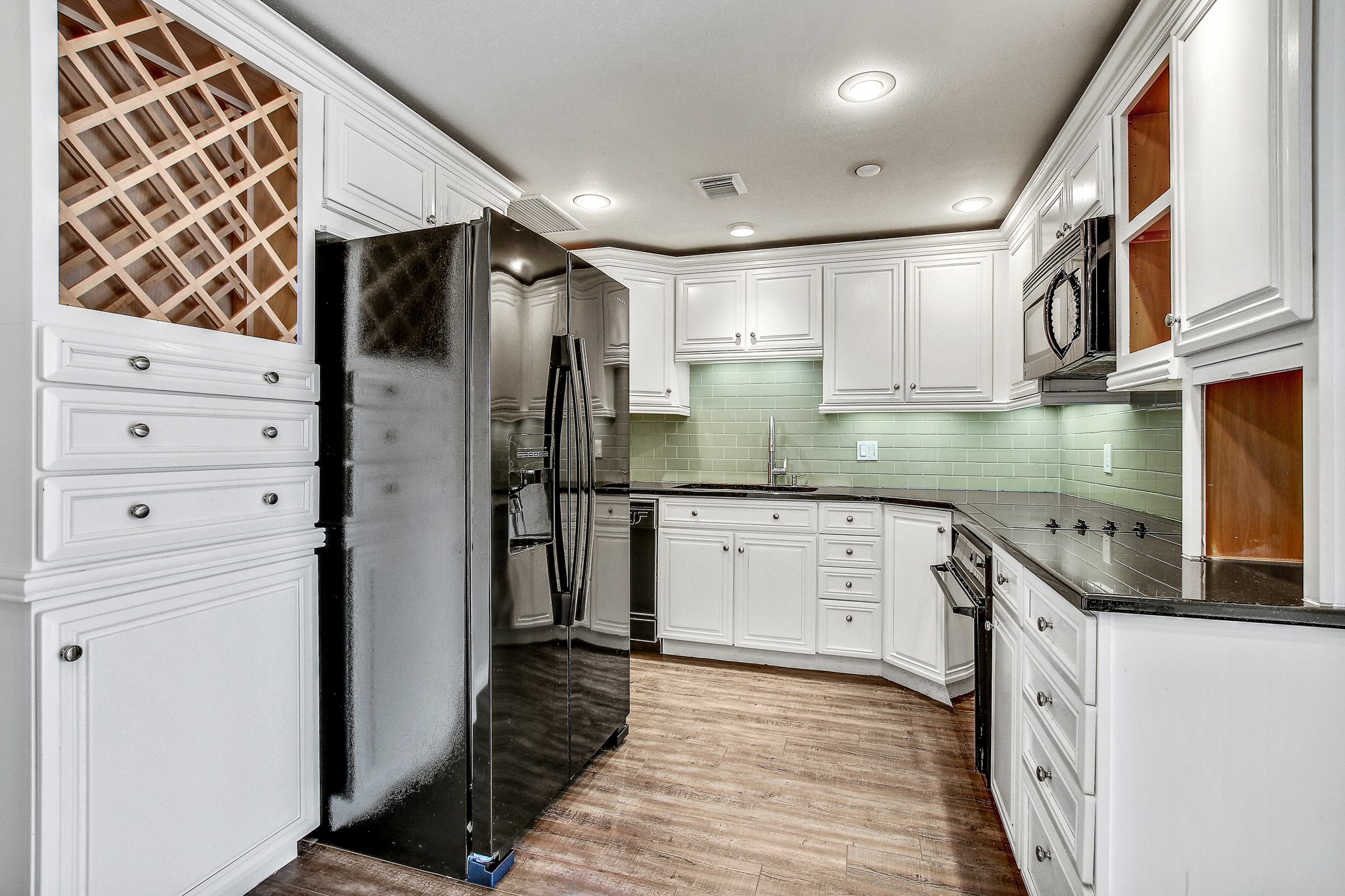 1801 Lavaca Street, Unit 5F Austin, TX 78701 - Photo 7 of 37 Kitchen with black appliances, white cabinets, black granite, tasteful backsplash, light wood-type flooring, and recessed lighting