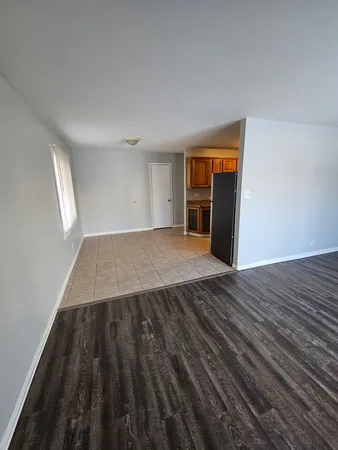 an empty room with wooden floor closet and windows