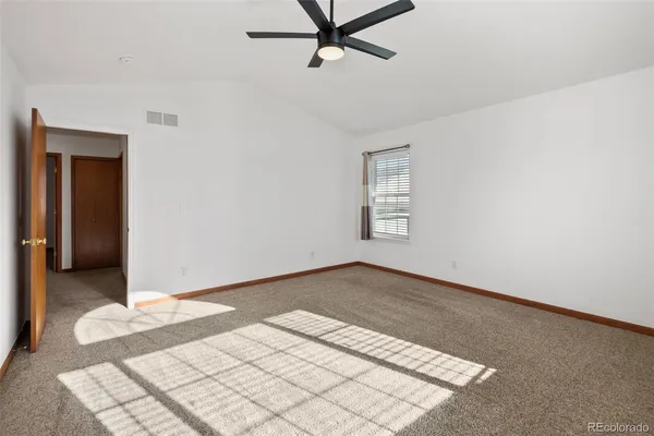 an empty room with windows and fan