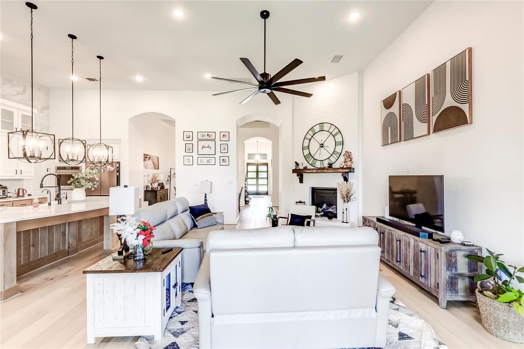 126 LITTLE Strm Cove Austin, TX 78737 - Photo 10 of 40 An open-concept living area boasts a fireplace and kitchen island, creating a harmonious and functional gathering space.