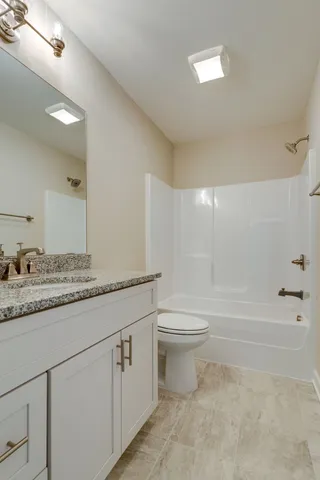 a bathroom with a granite countertop sink a toilet and bathtub