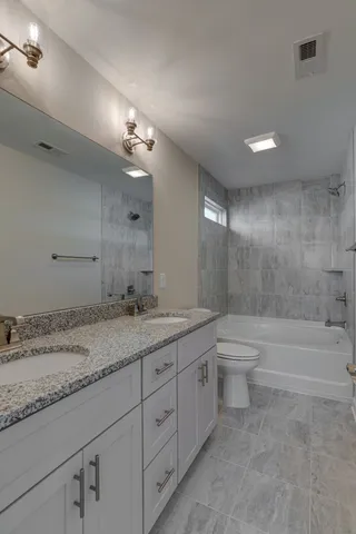 a bathroom with a granite countertop sink a toilet and bathtub