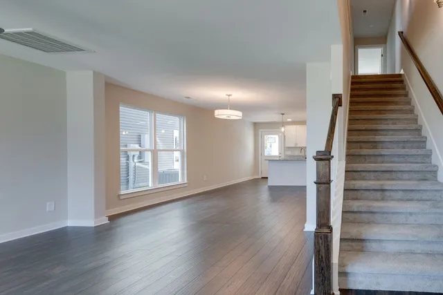 a view of an empty room with wooden floor and stairs