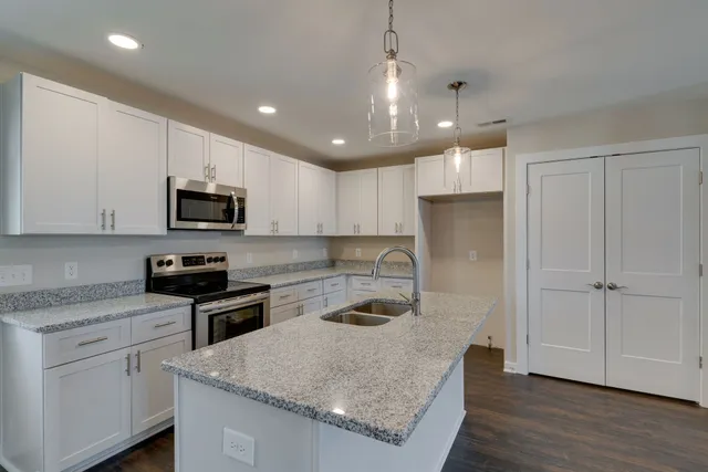 a kitchen with granite countertop a sink a counter space appliances and cabinets