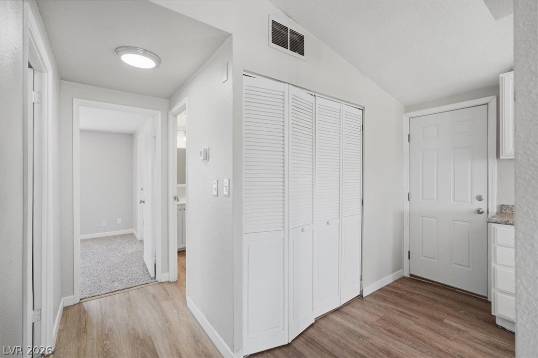 283 Aztec Lane Henderson, NV 89015 - Photo 11 of 21 A well-lit hallway with durable wood-look flooring connects various rooms within the home.