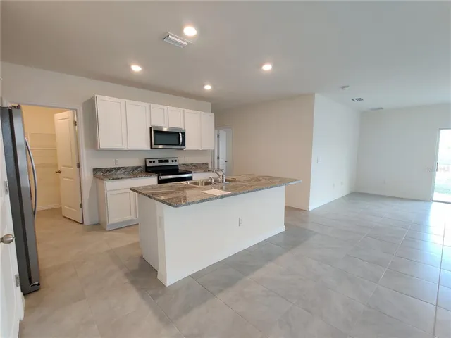 a kitchen with stainless steel appliances granite countertop a stove a sink and a refrigerator