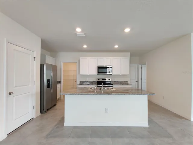 a kitchen with stainless steel appliances granite countertop a refrigerator a stove and a sink