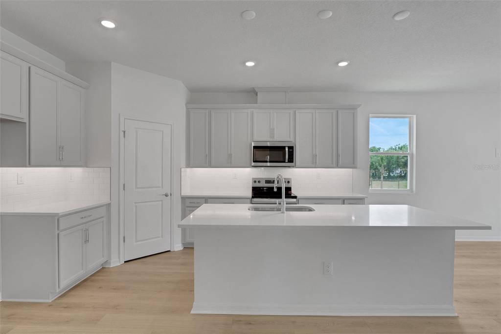 35424 Tuscan Hill Road Dade City, FL 33525 - Photo 22 of 42 a kitchen with kitchen island granite countertop a sink a counter top space and cabinets