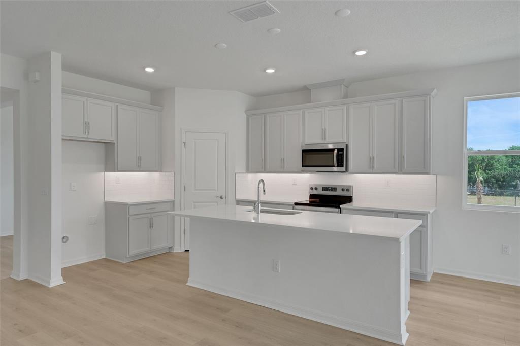 35424 Tuscan Hill Road Dade City, FL 33525 - Photo 23 of 42 a kitchen with kitchen island white cabinets and stainless steel appliances