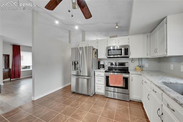 5255 Pinon Valley Road Colorado Springs, CO 80919 - Photo 10 of 47 Kitchen featuring white cabinets, tasteful backsplash, ceiling fan, and stainless steel appliances