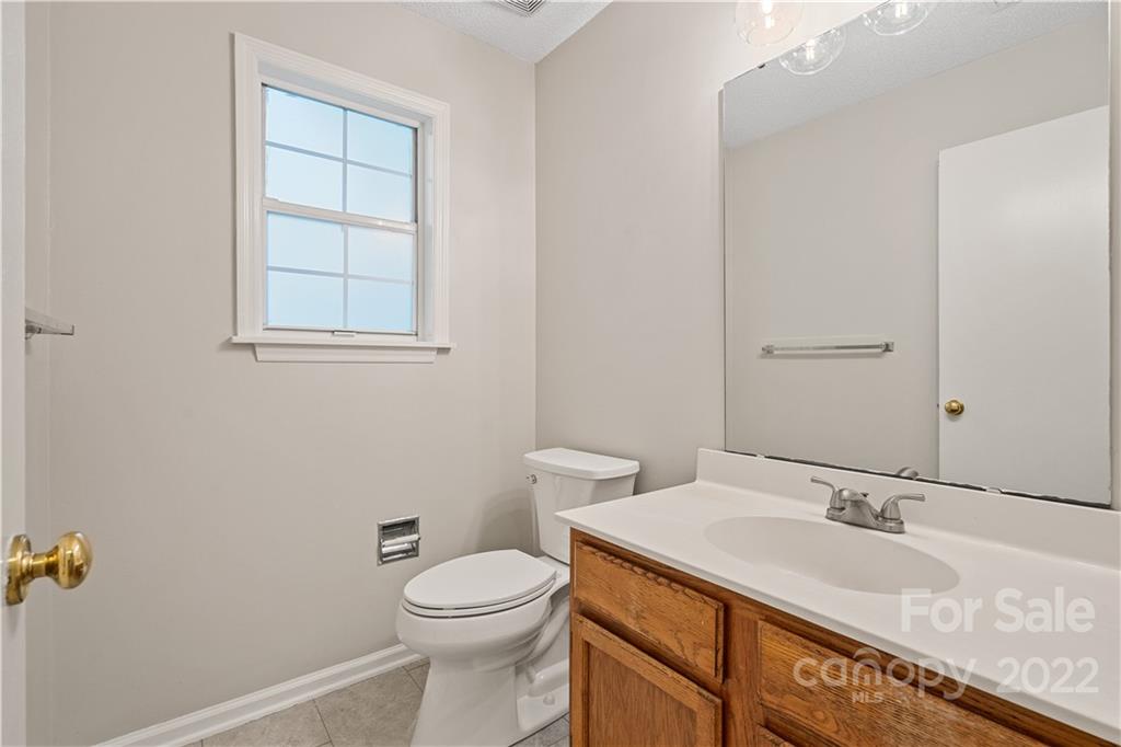 12021 Danby Road Pineville, NC 28134 - Photo 15 of 27 a bathroom with a granite countertop sink a toilet and a mirror