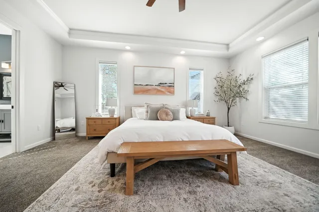 a bed sitting in a spacious bedroom next to a window and a larger closet