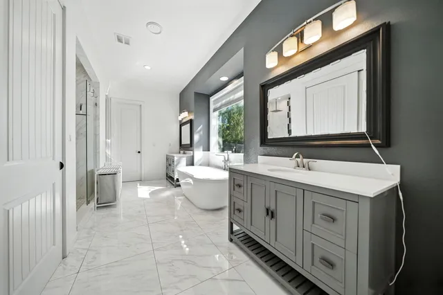 a spacious bathroom with a double vanity sink a toilet and a mirror