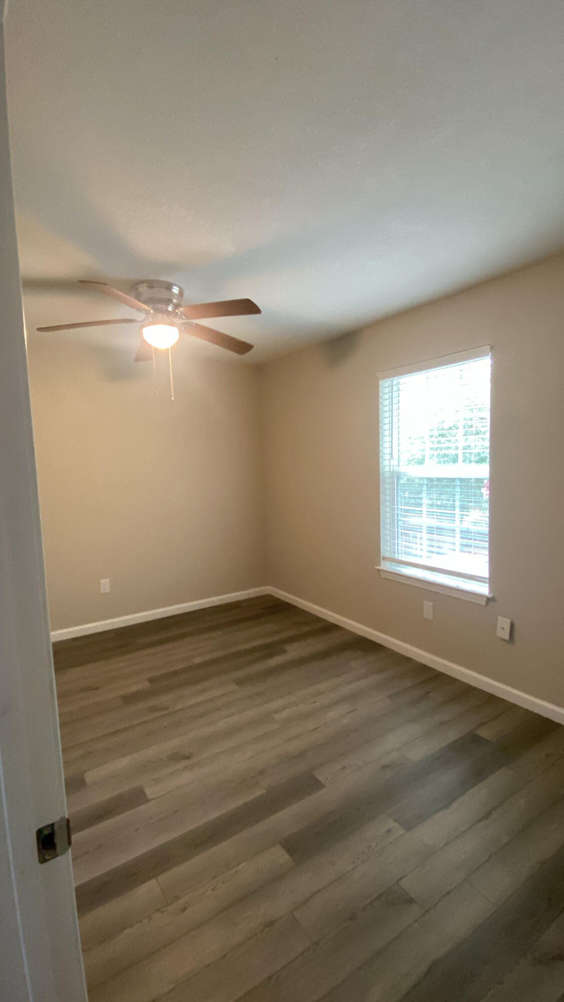 122 Hampton Drive Crestview, FL 32539 - Photo 8 of 12 a view of an empty room with wooden floor and a window