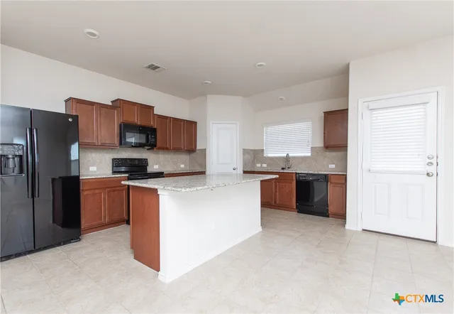 a large kitchen with stainless steel appliances granite countertop a refrigerator and a stove top oven