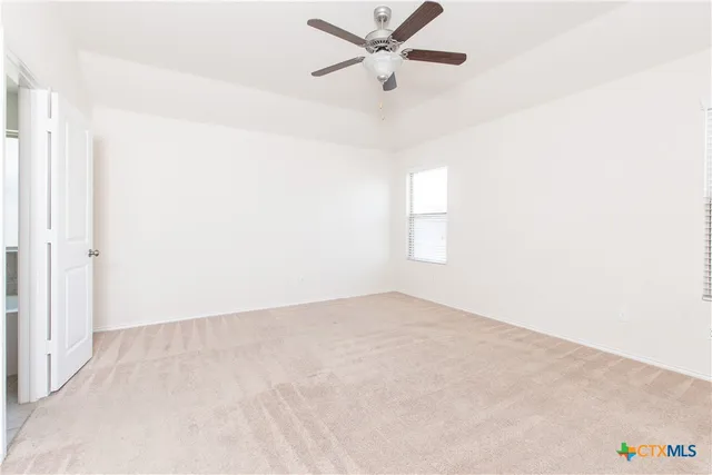 an empty room with a window and a fan