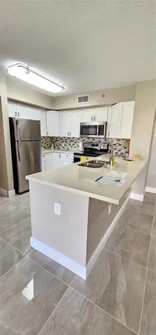 a kitchen with stainless steel appliances a refrigerator a stove a microwave and white cabinets
