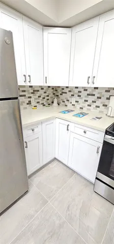 a view of kitchen with granite countertop white cabinets and white appliances