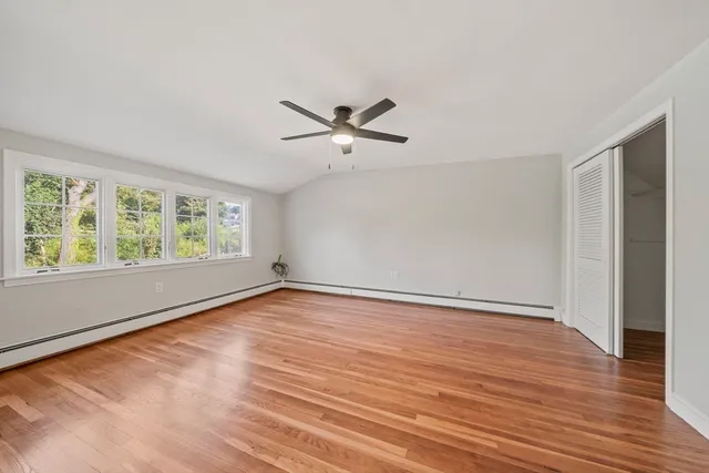 an empty room with wooden floor fan and windows