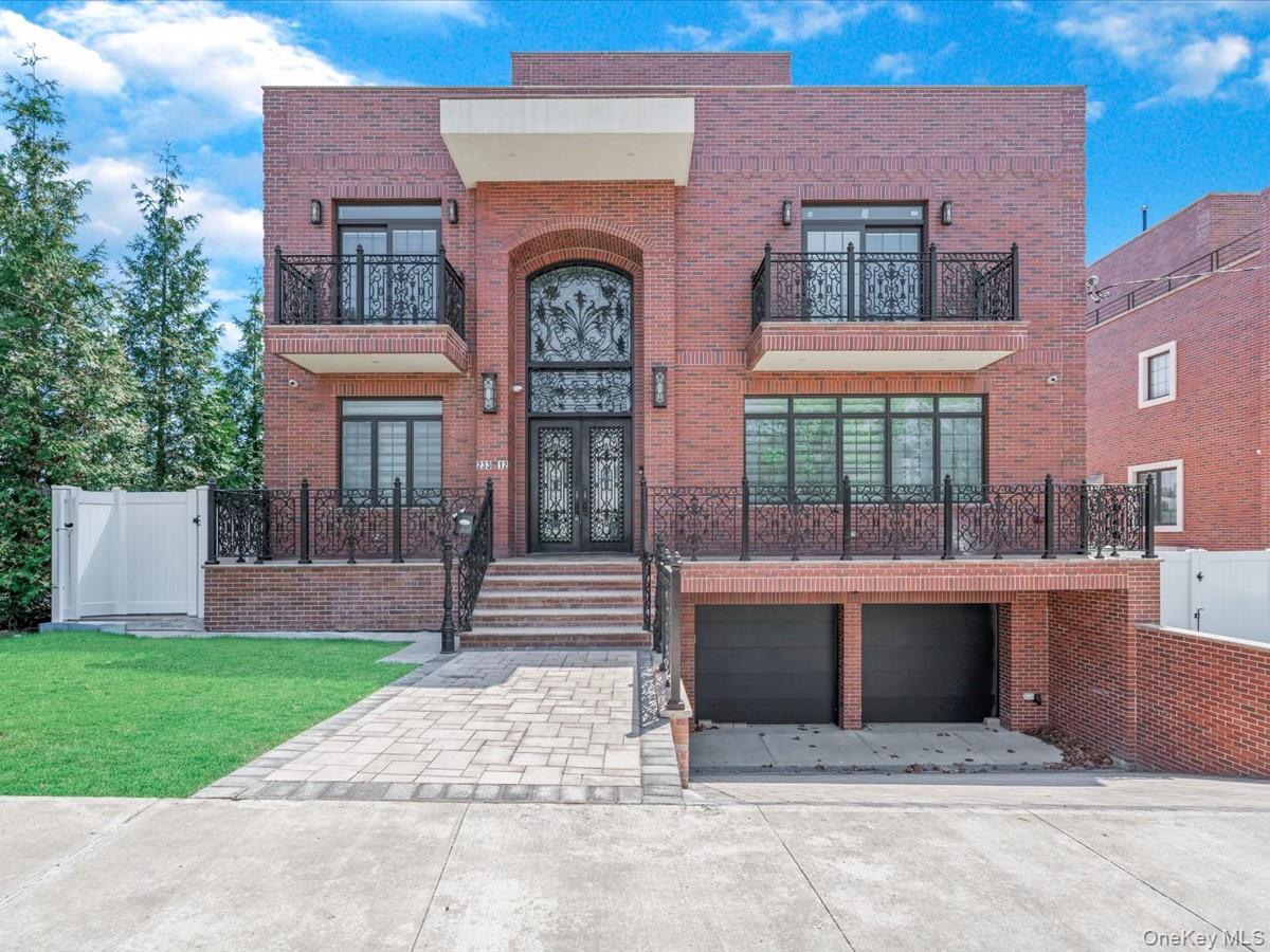233-12 Bay Street Queens, NY 11363 - Photo 1 of 46 View of front of home featuring brick siding, a balcony, driveway, and a gate