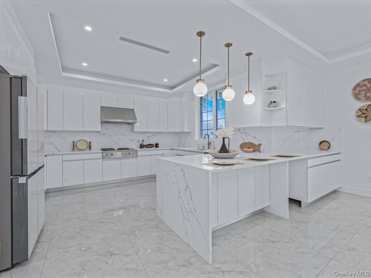 233-12 Bay Street Queens, NY 11363 - Photo 11 of 46 Kitchen with a tray ceiling, decorative backsplash, white cabinetry, a peninsula, and recessed lighting