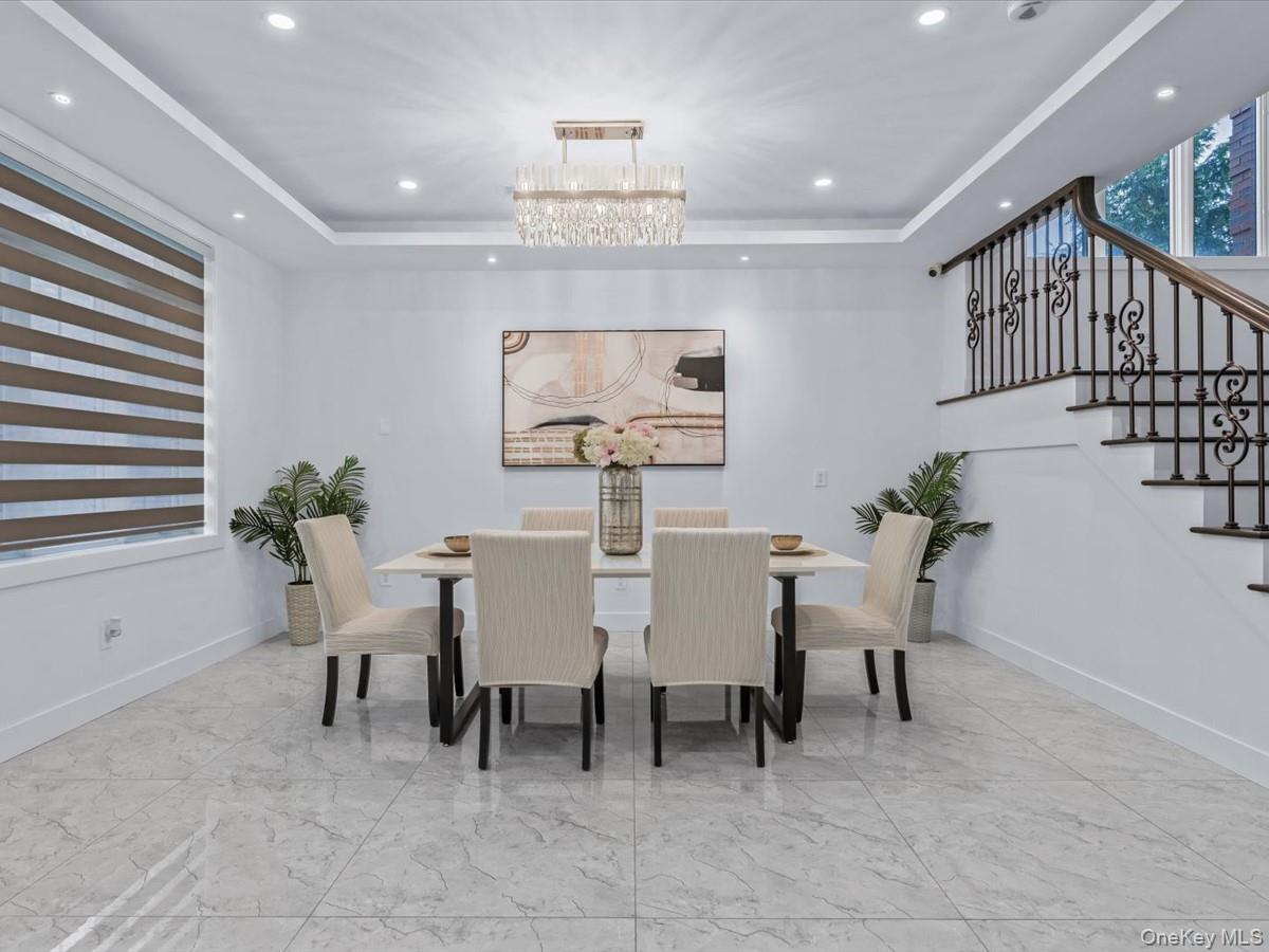 233-12 Bay Street Queens, NY 11363 - Photo 12 of 46 Dining area featuring a tray ceiling, stairs, recessed lighting, light marble finish flooring, and a chandelier