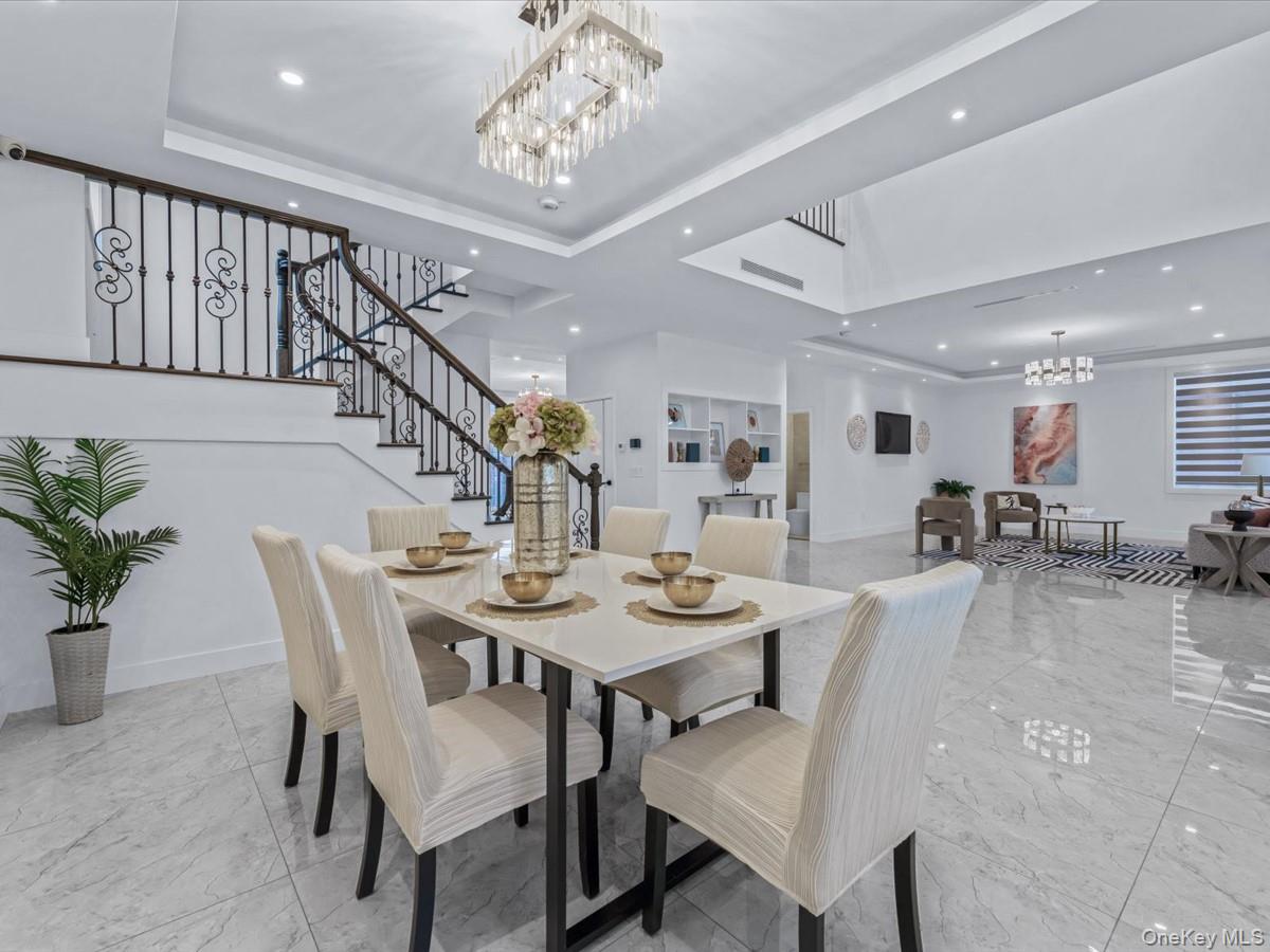 233-12 Bay Street Queens, NY 11363 - Photo 14 of 46 Dining area featuring a tray ceiling, a chandelier, stairs, recessed lighting, and light marble finish flooring