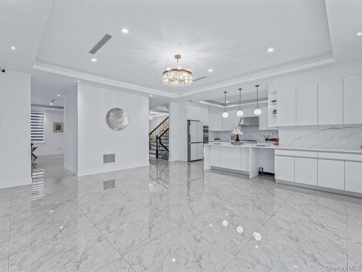 233-12 Bay Street Queens, NY 11363 - Photo 15 of 46 Unfurnished living room with a tray ceiling, recessed lighting, stairway, a chandelier, and light marble finish floors