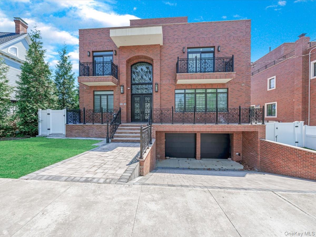 233-12 Bay Street Queens, NY 11363 - Photo 2 of 46 Contemporary house with brick siding, a balcony, concrete driveway, and a gate