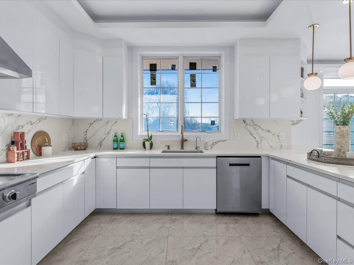 233-12 Bay Street Queens, NY 11363 - Photo 9 of 46 Kitchen with white cabinetry, modern cabinets, stainless steel dishwasher, and pendant lighting