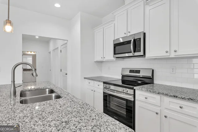 a kitchen with stainless steel appliances granite countertop a sink stove and microwave