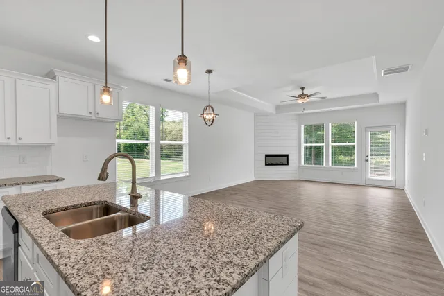 a kitchen with granite countertop a sink a counter space appliances and cabinets