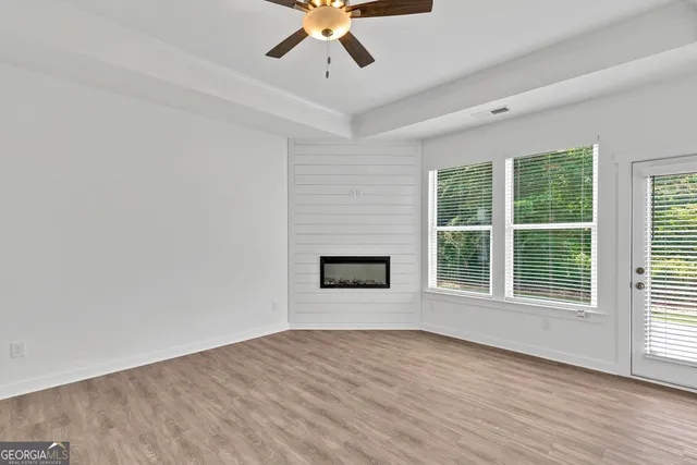 a view of empty room with wooden floor and fan